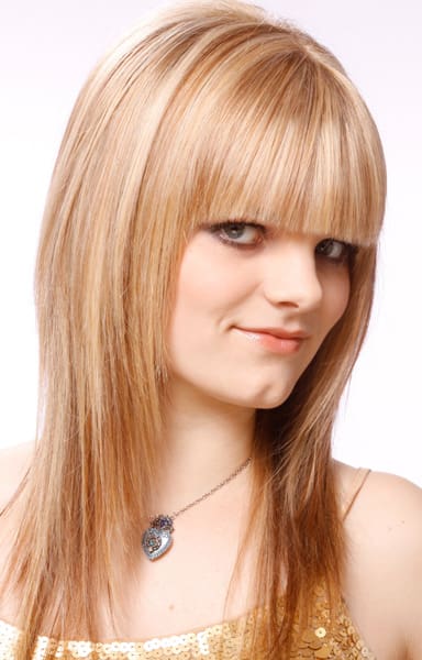 Natural-looking strawberry blonde hair color with haircut of long blunt bangs and angular framing layers.